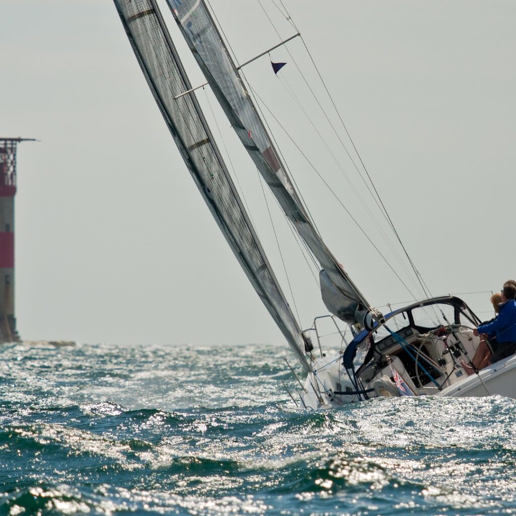 Sailing past The Needles, Isle of Wight. Sailing and Rowing impact the body. The Lymington Chiropractic Team can help support sailors and rowers to keep doing what they love.